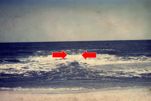 A rip current visible in the surf as a channel of churning water (marked with red arrows), photographed at the U.S. Army Corps of Engineers Field Research Facility, Duck, North Carolina