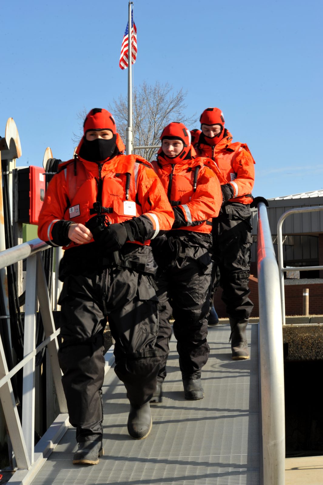 U.S. Coast Guard reserve Vessel Boarding and Security Team members in immersion gear walking into Curtis Creek in Baltimore, Maryland, during a cold-water survival training exercise