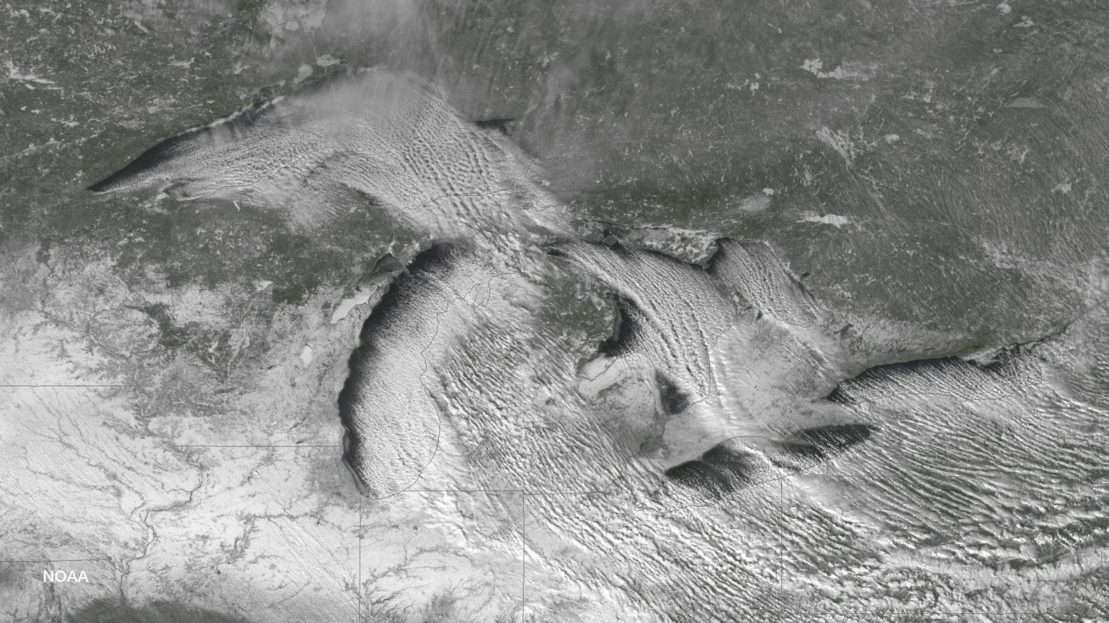 Satellite image of narrow lake-effect snow cloud bands streaming across the Great Lakes region